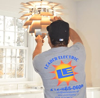 A man in a blue shirt is holding onto some lights
