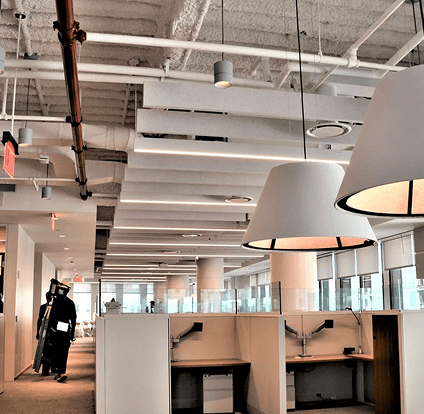 A person standing in an office with some lights hanging from the ceiling.