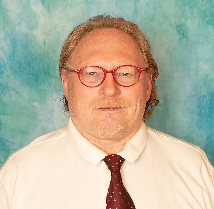 A man with long hair and glasses wearing a white shirt.