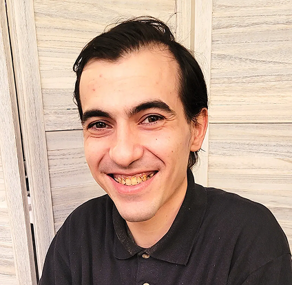 A man smiling for the camera with his hair combed back.