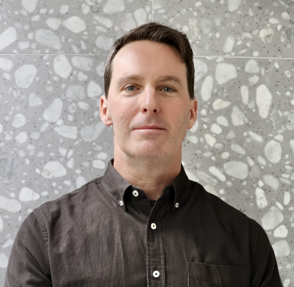 A man in black shirt standing next to wall.