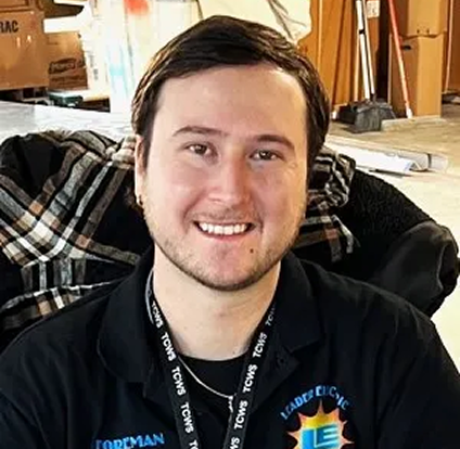 A man with long hair and a smile wearing a black shirt.